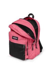 Sac à dos rose avec une finition texturée, poche avant en maille noire, double zippers et bretelles réglables. Logo de la marque visible à l'avant.