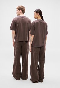 Brune, oversize t-shirts i bomuld kombineret med matchende bukser med vide ben, med syede detaljer og en lille logomærkat på bagsiden.