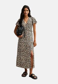 Maxiklänning i leopardmönster med korta volangärmar, omslagdesign, sidoflärp och matchad med svarta sandaler och en svart väska.