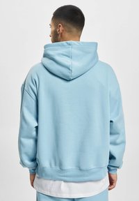 Lys blå hoodie med en stor hætte, løs pasform og ribbede manchetter. Den har en blød tekstur og et enkelt design, der gør den velegnet til afslappet brug.