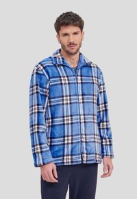 Chaqueta de forro polar a cuadros azules con un patrón de cuadros blancos y negros, cierre de cremallera y cuello. Textura suave, mangas largas y bolsillos laterales.