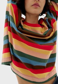 Gestreepte lange mouwen top met levendige kleuren: rood, geel, blauw, roze, groen en bruin. Zacht katoenmateriaal met een losse pasvorm en een bootnek.