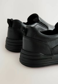 Bottes noires à enfiler avec une tige en cuir texturé, une épaisse semelle en caoutchouc et des languettes à l'arrière pour un enfilage facile.