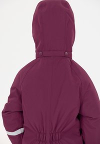 Mørkerød isoleret jakke med hætte, elastisk talje og reflekterende striber på ærmerne. Fremstillet af holdbart, vandafvisende materiale.