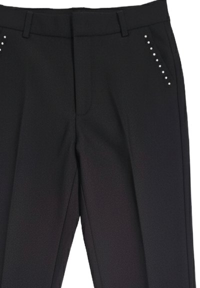 Pantaloni neri su misura con pieghe frontali e piccoli borchietti metallici che decorano le aree superiori delle tasche anteriori.