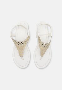 Sandales plates blanches avec un design à lanière T orné de strass transparents et dorés. Semelle lisse et détail de lanière tressée.