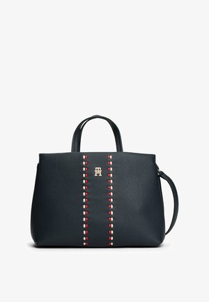 Granatowa skórzana torebka z podwójnymi uchwytami u góry, złotym logo i kontrastującym czerwonym oraz białym dekoracyjnym szyciem wzdłuż środka. Gładka tekstura.