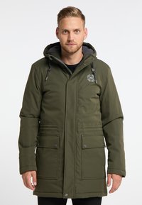 Olivgrön vadderad parkas med dragsko i huvan, två framfickor och logotypdetalj på bröstet. Slät yta, varm isolering.