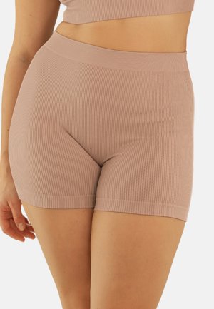 Nahaufnahme einer Person, die hoch taillierte, gerippte, hellbraune, eng anliegende Shorts und ein passendes, kurzes Oberteil trägt, wobei Torso und obere Oberschenkel sichtbar sind.