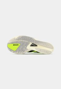 Suela de zapatilla de correr negra con acentos amarillo-verde, goma texturizada gris y marca "ADIZERO". Diseño aerodinámico para un mejor rendimiento.