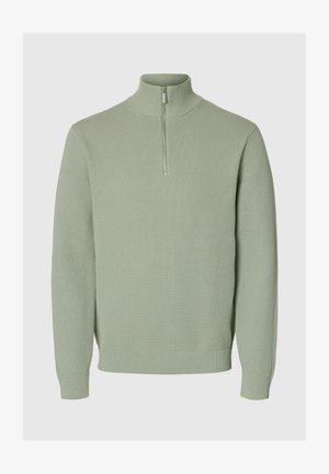 Lys grøn, ribbet strikpullover med høj krave og halv lynlås. Har lange ærmer og en tætsiddende talje.