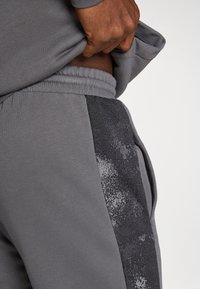 Γκρι αθλητικό παντελόνι με μονόχρωμο γκρι ύφασμα και σκούρη υφή ρίγα στο πλάι. Ελαστική μέση και ο ρατή πλαϊνή τσέπη.