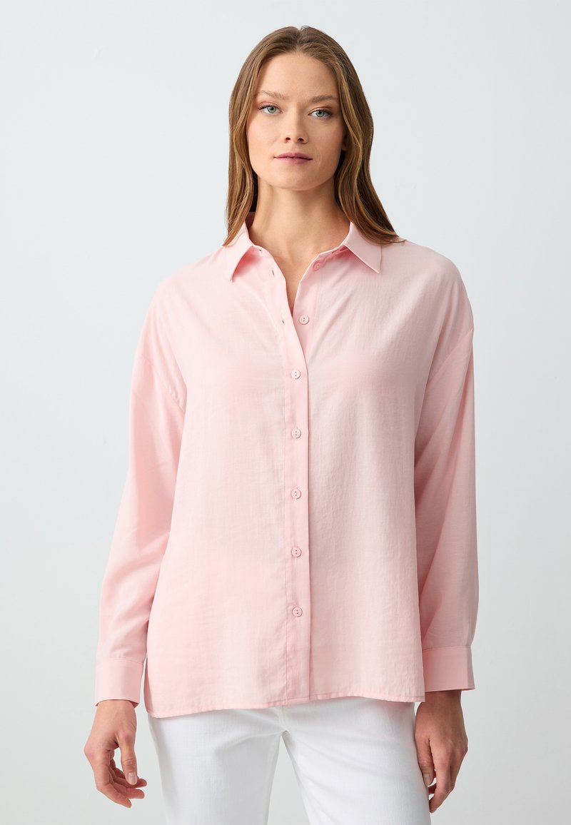 Lichtroze, lang mouwenshirt met knoopsluiting en kraag. Gemaakt van zachte stof met een losse pasvorm en een licht gebogen zoom.