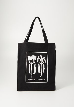 Borsa tote nera in tessuto, con un design grafico floreale bianco e testo. Due manici resistenti per il trasporto.