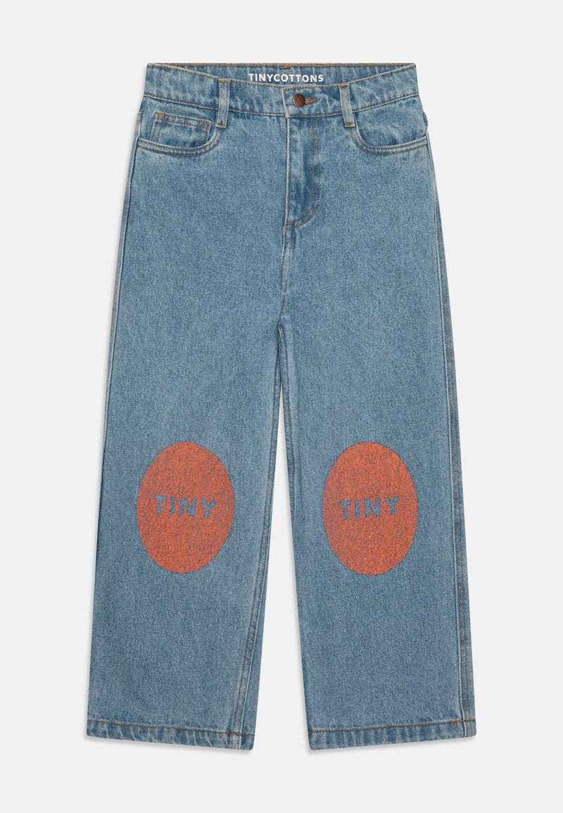 Os jeans de ganga azuis apresentam um design de pernas largas com remendos circulares laranja nos joelhos, cada um exibindo a palavra "TINY" em azul.