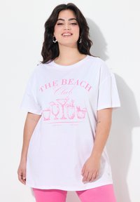 Weißes oversized T-Shirt mit pinkem Grafikdruck von Getränken und dem Text "THE BEACH Club." Mit kurzen Ärmeln und rundem Halsausschnitt.