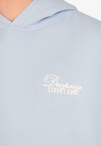 Hellblaues Hoodie mit weißem Text "Dropsize STREET GAME" auf der Brust, wobei ein Teil des Nackens und des Schulterbereichs sichtbar ist.