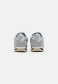 Nike könnyű kék velúr és hálós sneaker, párnázott bokával, dombornyomott logóval a sarkon, és kontrasztos tejszínszínű gumitalppal.