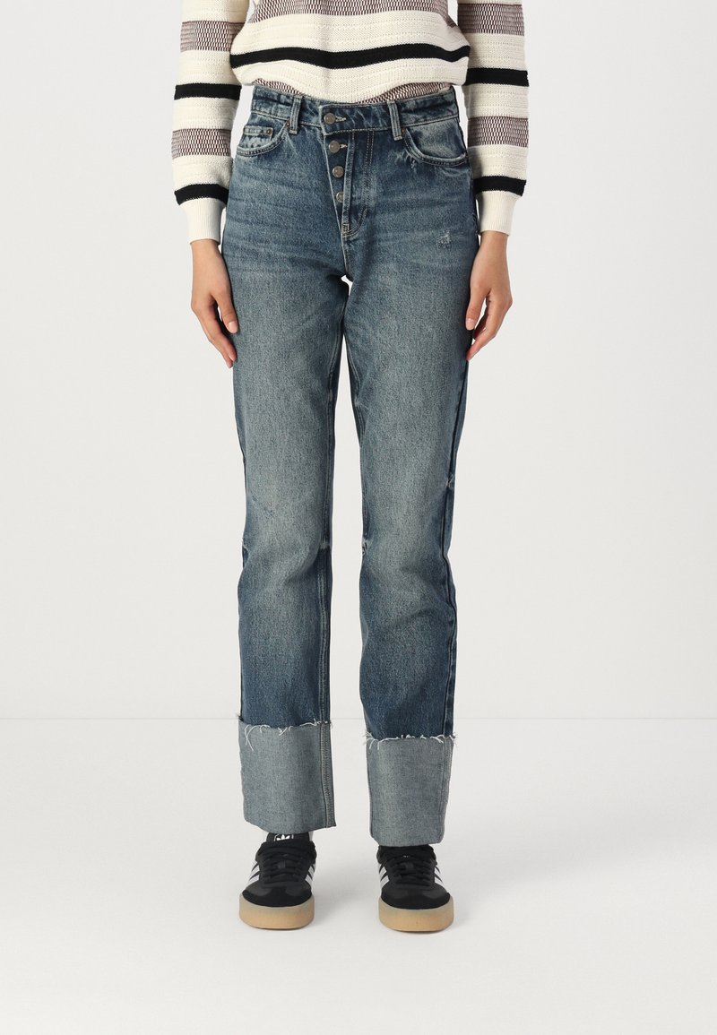 Ljusblå högmidjade jeans i blekt denim med rak ben, med fransar vid fållen och femknappsstängning, ihop med svarta sneakers.