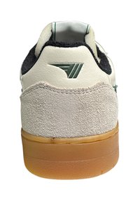 Sneaker met een witte lederen bovenkant en zwarte suède accenten, een gestructureerde grijze suède hak en een doorzichtige gumrubberen zool.