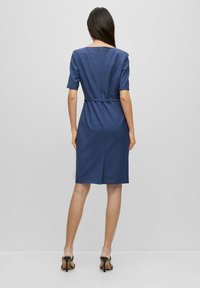Robe bleu marine à manches courtes, taille cintrée par une ceinture, longueur genou, avec un léger motif texturé et une fermeture éclair au dos.