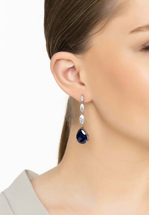Drop earrings featuring a deep blue teardrop gemstone, silver accents, and a series of smaller clear gemstones, hanging below the earlobe.