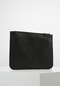 Funda de cuero negro con una textura suave, forma rectangular y cierre de cremallera plateada. Presenta un logotipo grabado en un lado.