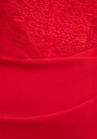 Rødt tøj med glat stof og blonder øverst. Teksturen er blød, og designet omfatter en tætsiddende form med lagdelte sektioner.