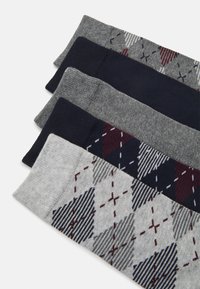 Négy pár szürke és tengerészkék zokni, amelyek között egyaránt találhatók egyszínű és argyle mintás modellek. Puha kötött anyagból készültek, hangsúlyozva a textúrát és a dizájnt.