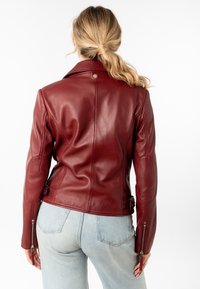 Rode leren motorjack met een getailleerd ontwerp, schouderepauletten, zijgespen en ritsdetails op de mouwen.
