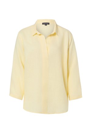 Jasnożółta, długorękawowa koszula zapinana na guziki z klasycznym kołnierzem, gładkim materiałem i ukrytymi guzikami z przodu, prezentowana na białym tle.