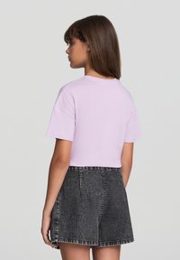 T-shirt viola chiaro a maniche corte realizzato in morbido cotone, abbinato a pantaloni corti in denim neri a vita alta con orlo sfilacciato.