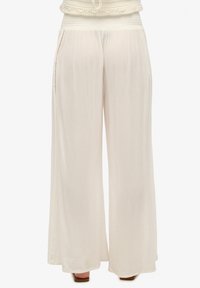 Pantalones de pierna ancha, livianos, en color crema, con un tejido texturizado y fluido y una cintura fruncida con bolsillos en las costuras laterales.