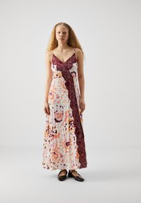 Maxi-Kleid mit einem floralen Muster in Orange, Pink und Lila. Es hat einen tiefen Ausschnitt, bordeauxfarbene Spitzenbesätze und Spaghettiträger.