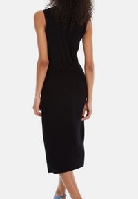 Schwarzes ärmelloses knielanges Kleid mit tailliertem Bund und weiter Rock, aus weichem Stoff gefertigt, mit glatter Textur und minimalistischem Design.