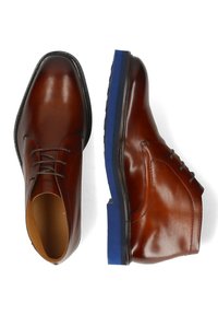 Zapatos de cuero marrón con un acabado suave, diseño de cordones y suela acentuada en azul. La forma es clásica con una puntera redondeada.