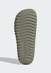 Podošva Adidas topánky, s vlnitým dizajnom v tlmených zelených odtieňoch, s textúrovanými povrchmi a vyrazeným brandingom na boku.