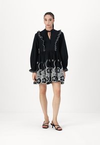 Μαύρο φόρεμα με λευκή floral κεντητική, ριχτό γιακά, μακριά μανίκια και φουσκωτό φούστα. Συνδυάζεται με μαύρες λουρίδες τακούνια.