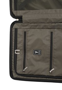 Organizzatore in tessuto verde oliva con tre scomparti con zip, tasca in rete nella parte superiore e dettagli in zip neri. Patch del logo sulla parte anteriore.