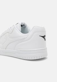 Sneaker atletica bianca con tomaia in pelle liscia, collo imbottito, dettaglio logo nero e suola in gomma texturizzata.