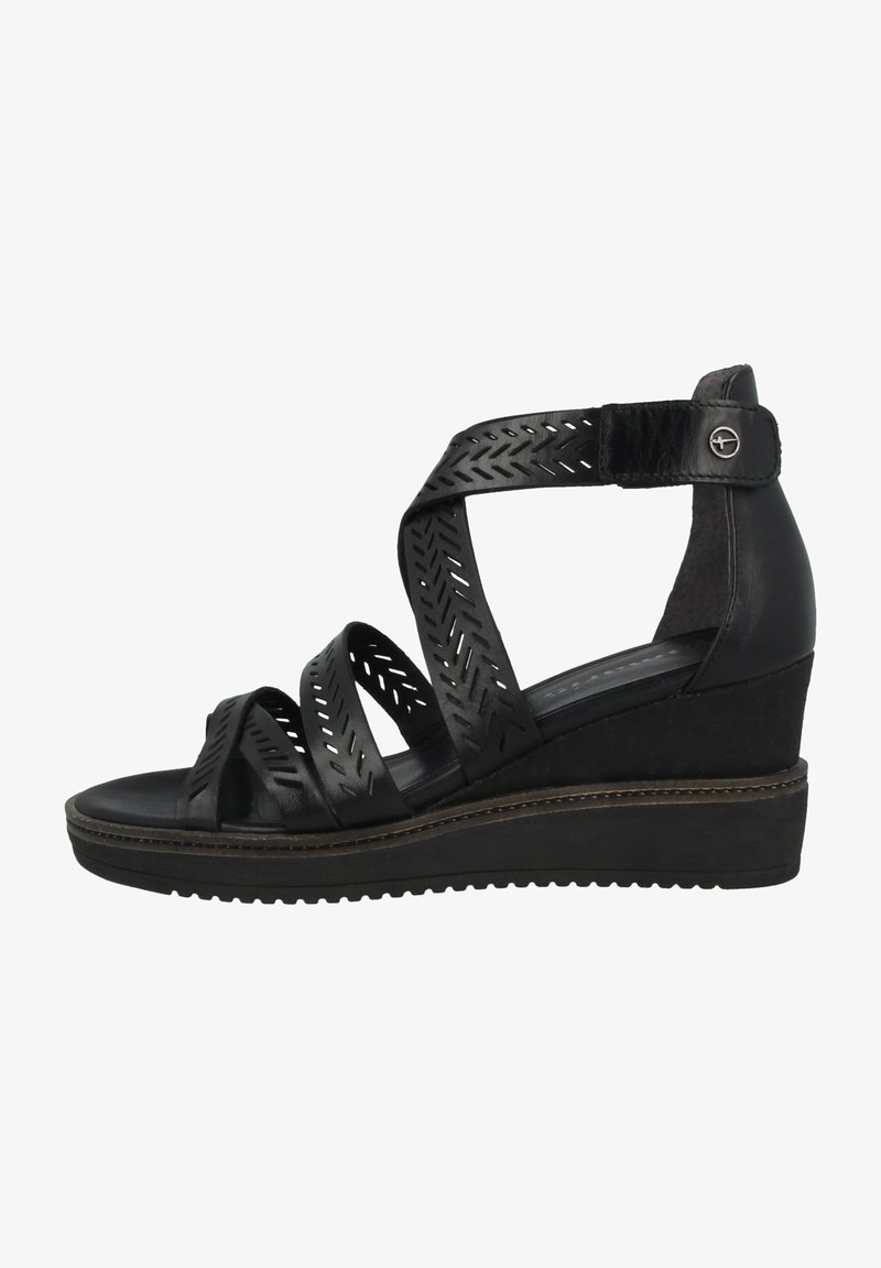 Sandales compensées noires avec des brides croisées, présentant des découpes. La semelle a une bande de roulement texturée et un accent marron contrastant le long du bord.