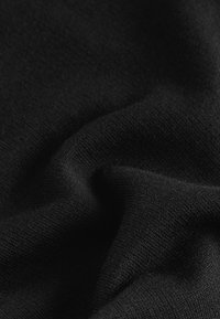 Schwarzer Strickstoff mit einer weichen, feinen Textur und einer glatten Oberfläche. Das Material zeigt dezente Dehnungen und Falten.