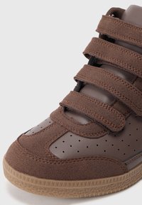 Braune High-Top-Sneaker aus Wildleder und Leder, mit verstellbaren Klettverschlüssen, durchbrochendem Design und einer strukturierten Gummisohle.