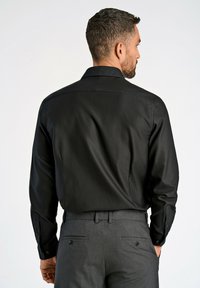 Zwarte button-up shirt van gladde stof, met een gestructureerde kraag en lange mouwen, gecombineerd met grijze op maat gemaakte broek.