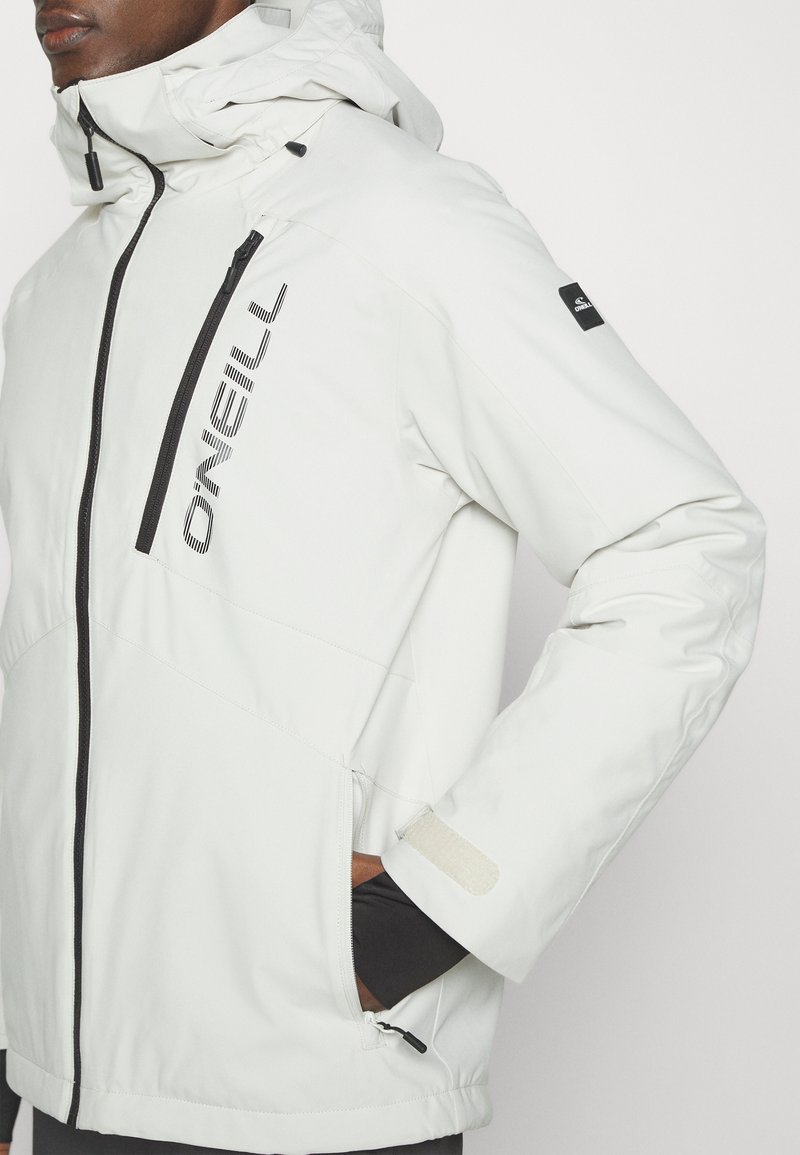 Weiße wetterfeste Jacke mit Reißverschlusstaschen, verstellbarem Kapuze und schwarzen Akzenten. Das Material wirkt glatt und leicht mit einem eleganten Design.