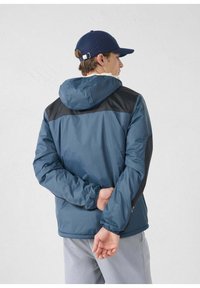 Chaqueta con capucha para hombre en azul con detalles en negro. Material resistente al agua, puños elásticos y un ajuste holgado. Cuenta con una capucha espaciosa.