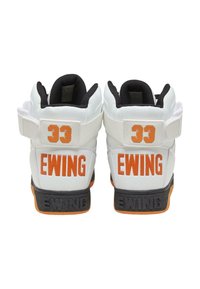Baskets montantes blanches avec des accents noirs, arborant un logo orange "33" et "EWING". Fabriquées en cuir avec une semelle texturée. Avec une sangle réglable.