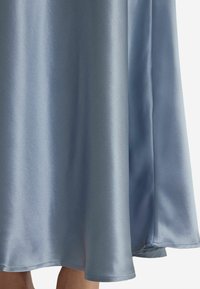Robe en satin bleu clair, présentant une texture lisse, une coupe fluide et un ourlet qui tombe gracieusement. Aucun motif ou accent notable visible.
