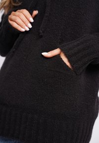 Czarna dzianinowa bluza z kapturem o fakturowanym wykończeniu, z kieszenią z przodu i prążkowanymi ściągaczami. Materiał wydaje się miękki i ciepły.