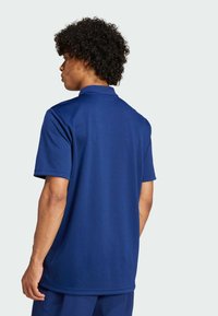 Marineblauwe polo met korte mouwen en een klassieke kraag. Gemaakt van gladde stof met een relaxte pasvorm, met een effen kleurontwerp.